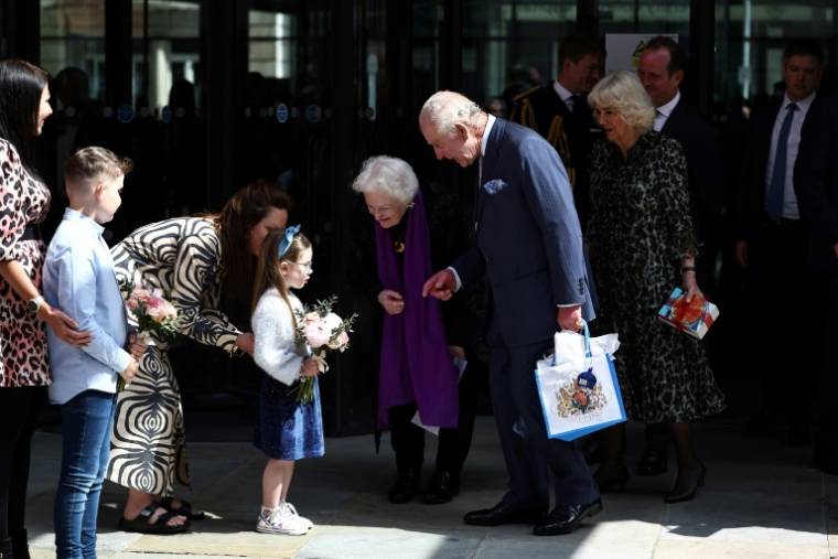 Le roi Charles III et Camilla reçoivent un bouquet de fleurs après une visite au centre Macmillan de l'University College Hospital de Londres, le 30 avril 2024 ( AFP / HENRY NICHOLLS )