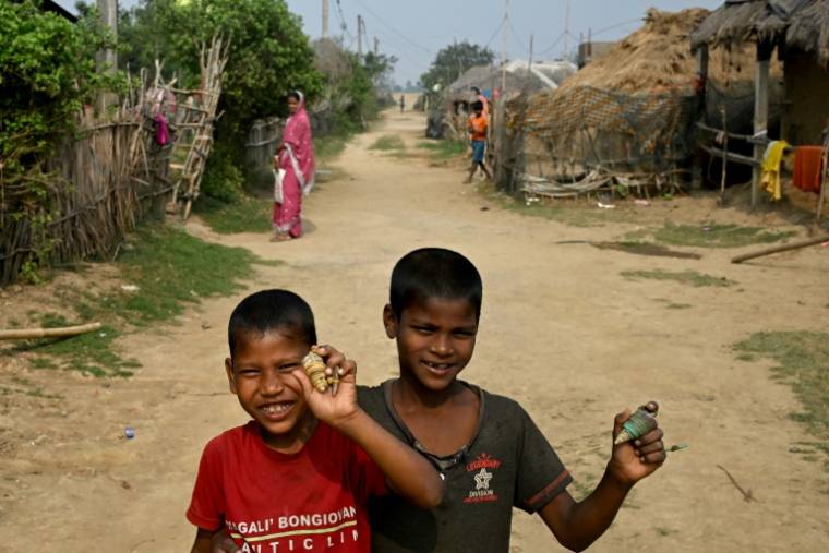Photo prise le 27 février 2024 d'enfants jouant avec des coquillages à Bagapatia, un village côtier de l'est de l'Inde où on été relogés les habitants du village de Satabhaya, victime de la montée des eaux ( AFP / Dibyangshu SARKAR )