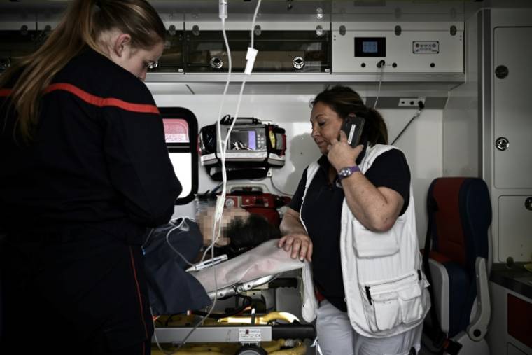 Pascale Martinet (d), infirmière anesthésiste et membre de l'une des premières unités hospitalières mobiles paramédicales (UMH-P) du CHU de Bordeaux, parle au téléphone dans un camion de pompiers utilisé pour transporter un patient suite à un appel d'urgence, le 17 avril 2024 à Bordeaux ( AFP / Philippe LOPEZ )