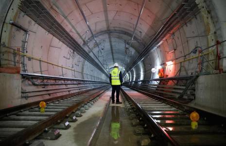 De dos, un employé de la Société des grands projets se tient dans le tunnel avant la dernière soudure des rails de la ligne 15 Sud du nouveau « Grand Paris Express », à la station de métro Clamart le 3 avril 2024. ( AFP / LUDOVIC MARIN )