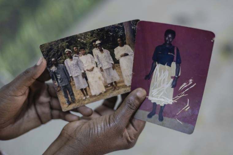 Nyirahabimana Aliette, survivante du génocide rwandais, montre des photos des membres de sa famille tués en 1994, pour qu'elles soient dessinées dans un atelier d'artistes, le 2 avril 2024 à Kigali, au Rwanda ( AFP / Guillem Sartorio )