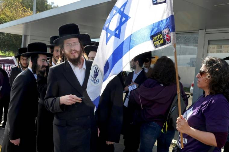 Des manifestants et des juifs orthodoxes devant un bureau de recrutement de l’armée dans la ville de Kiryat Ono, près de Tel Aviv, le 5 mars 2024, lors d’une manifestation contre leur exemption du service militaire ( AFP / JACK GUEZ )
