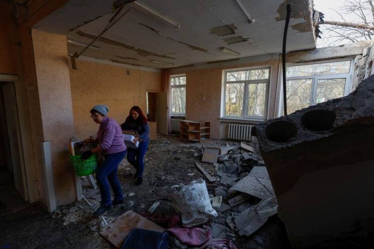 Des employés transportent des objets à l'intérieur d'un bâtiment d'école maternelle endommagé lors d'attaques de drones russes