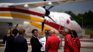 Le président Emmanuel Macron (c) écoute les agents de la sécurité civile lors de sa visite à la base aérienne des pompiers de Nîmes-Garons, le 2 juin 2023 à Garons, dans le Gard ( POOL / Daniel Cole )