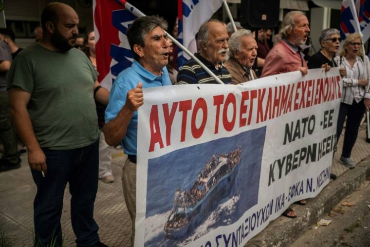 Des manifestants devant le tribunal de Kalamata, en Grèce, avec une bannière "Ils sont coupables de ce crime" à l'ouverture du procès de neuf Egyptiens accusés d'être impliqués dans l'un des naufrages de migrants les plus meurtriers en Méditerranée, le 21 mai 2024  ( AFP / Angelos TZORTZINIS )
