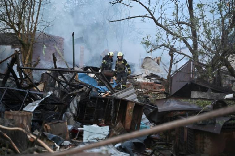 Des pompiers déblaient des débris après une attaque de drones russes sur des maisons des environs de Kharkiv, le 21 mai 2024 en Ukraine ( AFP / SERGEY BOBOK )