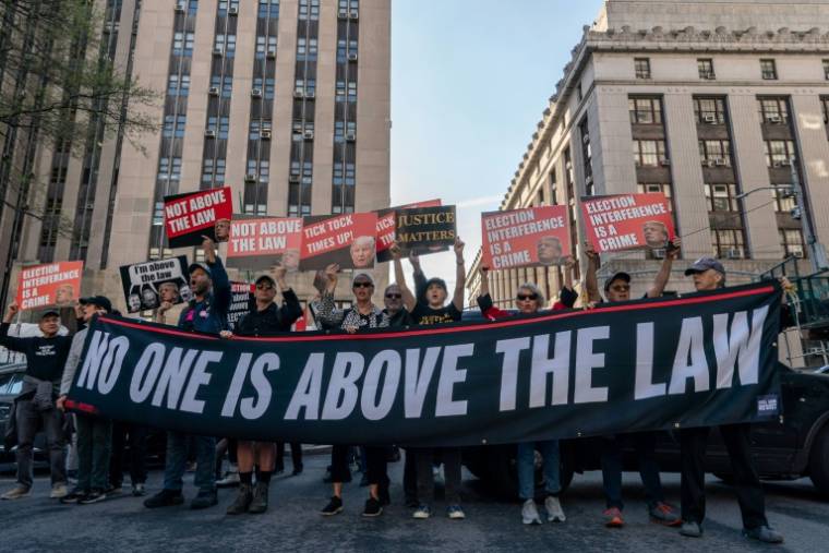 Des manifestants tiennent une banderole "personne n'est au-dessus des lois" au pied du tribunal de Manhattan où se déroule le procès de Donald Trump, à New York le 16 avril 2024 ( AFP / Adam Gray )