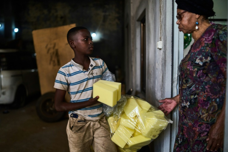 Un garçon vend du polystyrène à la patronne de l'atelier de cercueils, Amelia Armando Machava, le 10 octobre 2024 à Beira ( AFP / Zinyange Auntony )