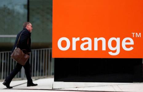 Un homme passe devant le logo Orange près de Paris