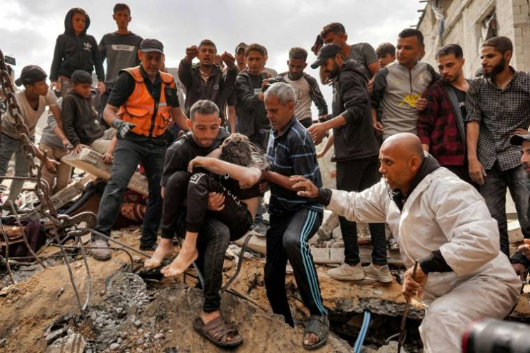 Un Palestinien porte le corps d'un garçon sorti des décombres d'un bâtiment effondré après un bombardement israélien à Nousseirat, dans le centre de la bande de Gaza, le 14 mai 2024 ( AFP / - )