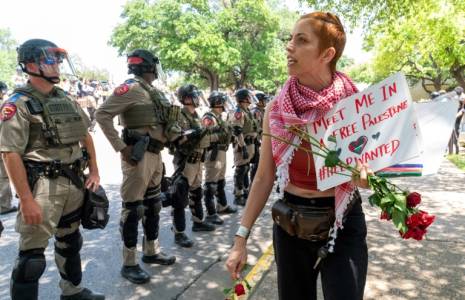 Une manifestante pro-palestinienne passe devant des soldats à l'Université du Texas à Austin (Etats-Unis), le 29 avril 2024 ( AFP / SUZANNE CORDEIRO )