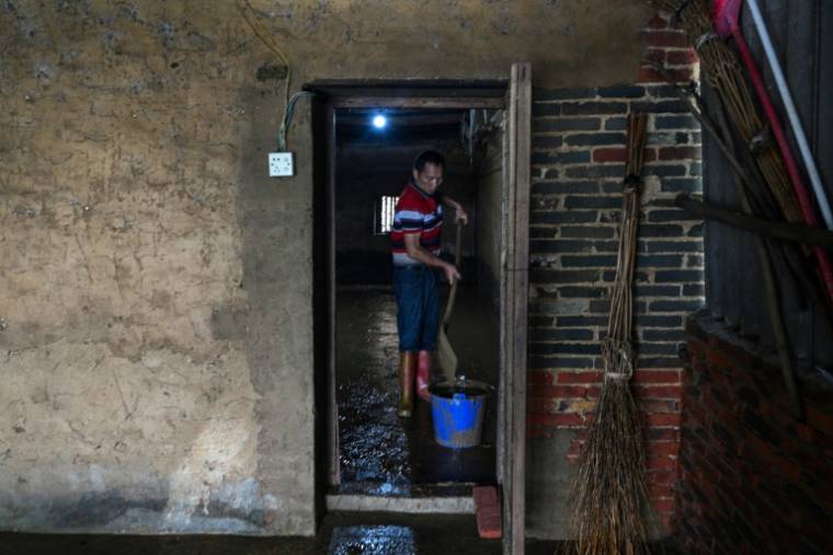 Lan Zhukui nettoie la boue de l'entrepôt où se trouvait son élevage de vers à soie, dans le village de Sancun, à Yingde, dans la province chinoise du Guangdong, le 25 avril 2024 ( AFP / Hector RETAMAL )