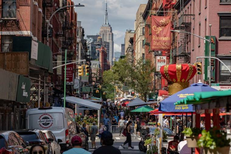 Des gens marchent dans une rue bordée de restaurants dans le quartier de Little Italy à Manhattan