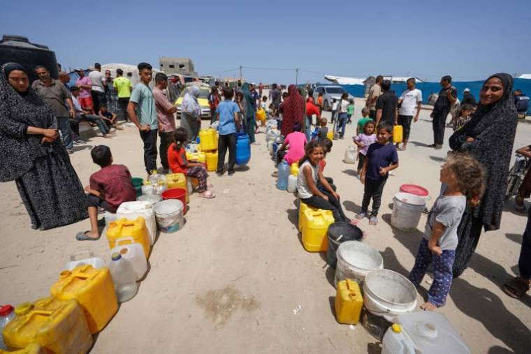 Des déplacés palestiniens font la queue pour obtenir de l'eau dans un camp à l'ouest de Deir al-Balah, dans le centre de la bande de Gaza, le 21 mai 2024 ( AFP / - )