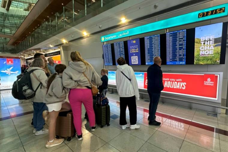 Des voyageurs regardent le tableau des vols au départ à l'aéroport de Dubaï, le 17 avril 2024 aux Emirats arabes unis ( AFP / - )