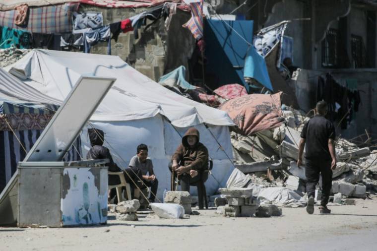 Des déplacés palestiniens sont assis devant une tente le 15 mai 2024 à Deir el-Balah, dans le centre de la bande de Gaza, où une guerre oppose Israël au mouvement islamiste palestinien Hamas ( AFP / - )