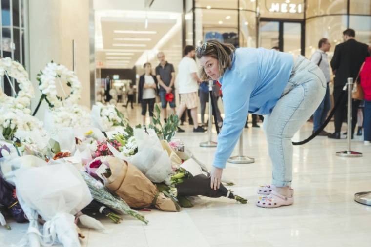Une femme rend hommage aux victimes de l'attaque meurtrière du centre commercial Westfield Bondi Junction à Sydney lors de sa réouverture le 18 avril 2024, une semaine après le drame  ( POOL / Dion Georgopoulos )