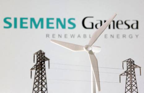 Des miniatures d'éoliennes et de poteaux électriques devant le logo de Siemens Gamesa