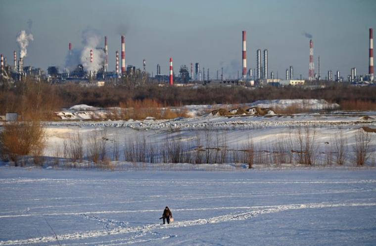 Un homme marche près d'une raffinerie de pétrole à Omsk, en Russie