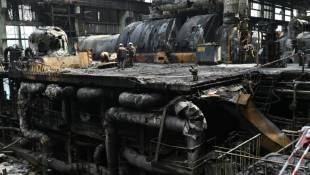 Des ouvriers nettoient les débris d'équipements calcinés dans une centrale électrique du fournisseur d'énergie DTEK, détruite après une attaque de missiles russes, le 19 avril 2024 en Ukraine  ( AFP / Genya SAVILOV )
