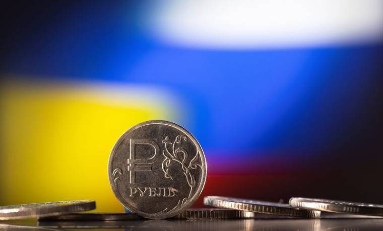 Image d'illustration montre des pièces en rouble russe devant des drapeaux ukrainiens et russes