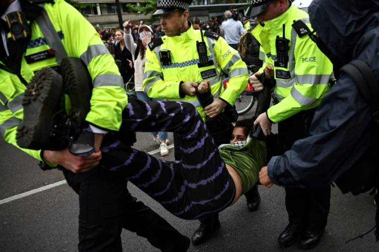 Des policiers arrêtent des manifestants rassemblés autour d'un bus en attente de transporter des migrants et des demandeurs d'asile d'un hôtel de Peckham, au sud de Londres, vers la barge Bibby Stockholm à Portland, dans le Dorset, au sud-ouest de l'Angleterre, le 2 mai 2024 ( AFP / HENRY NICHOLLS )