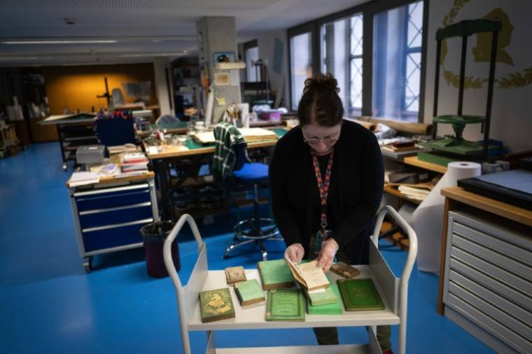 Aude Therstappen, conservatrice de la BNU (Bibliothèque nationale et universitaire) à Strasbourg, examine des livres colorés en vert avec l'arsenic, le 17 mai 2024 ( AFP / SEBASTIEN BOZON )