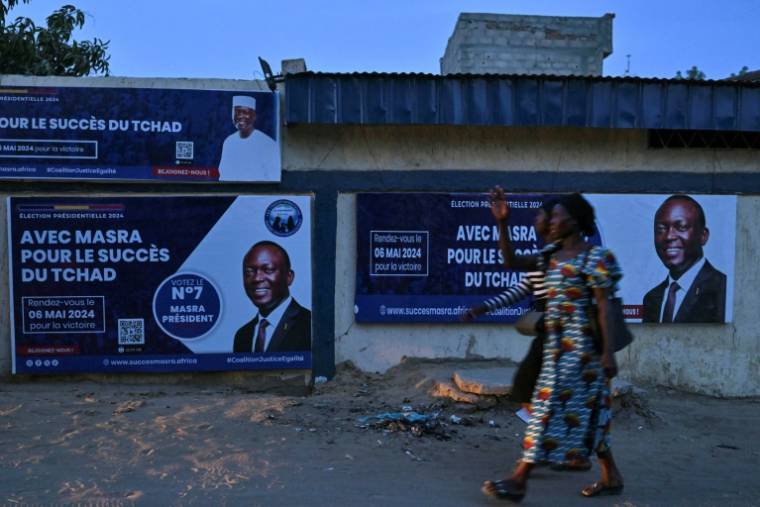 Des gens passent devant une affiche de campagne de Succès Masra, candidat à la présidentielle tchadienne, le 4 mai 2024 à N'Djamena  ( AFP / Issouf SANOGO )