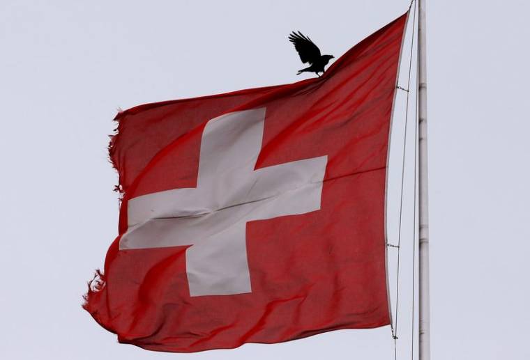 Un oiseau se pose sur un drapeau national suisse à Zurich