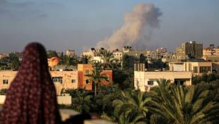 Une Palestinienne regarde de la fumée s'élever après une frappe isaélienne au sud de la ville de Gaza le 11 juin 2024 ( AFP / Eyad BABA )