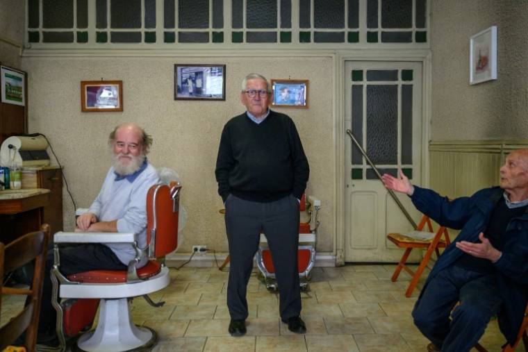 Le coiffeur Roger Amilhastre (C), âgé de 90 ans, dans son salon à Saint-Girons, en Ariège, le 16 avril 2024  ( AFP / Ed JONES )