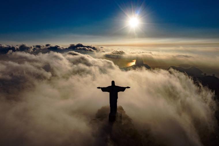 Le soleil se lève devant la statue du Christ Rédempteur à Rio de Janeiro, au Brésil, le 24 mars 2021.  ( AFP / CARL DE SOUZA )