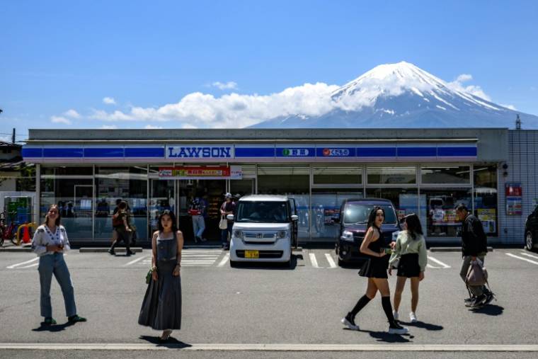 Des touristes dans une rue de la ville de Fujikawaguchiko avant l'installation d'un vaste filet pour cacher la vue du Mont Fuji, le 3 mai 2024 au Japon ( AFP / Philip FONG )