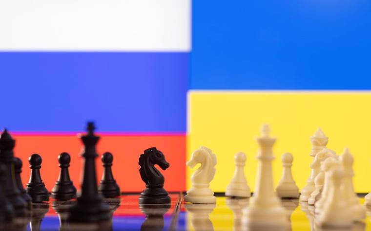 Des pièces de jeu d'échec devant les drapeaux de la Russie et de l'Ukraine