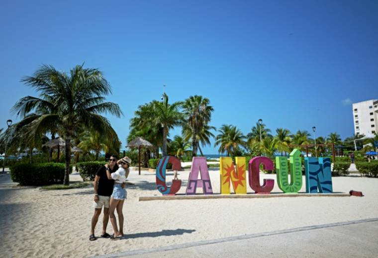 Un couple se prend en photo sur la plage à Cancun au Mexique le 23 avril 2024.  ( AFP / CARL DE SOUZA )
