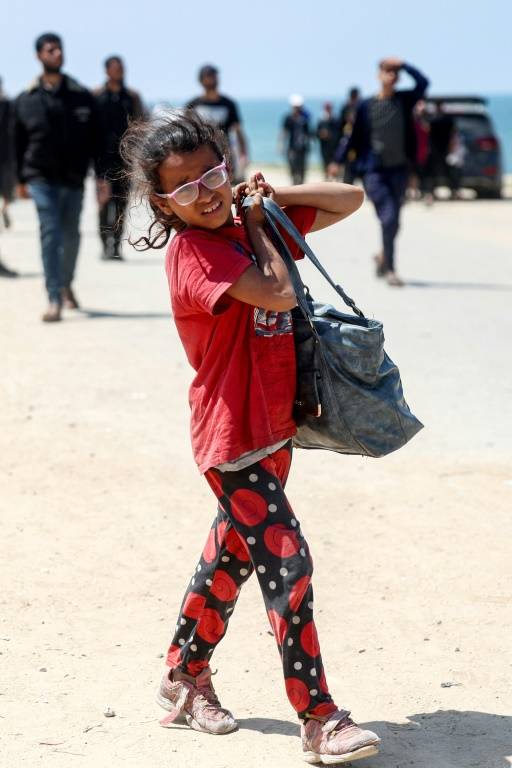 Une fillette porte un sac sur la route côtière de la bande de Gaza où des milliers de Palestiniens déplacés tentent de regarder le nord, le 14 avril 2024 ( AFP / - )