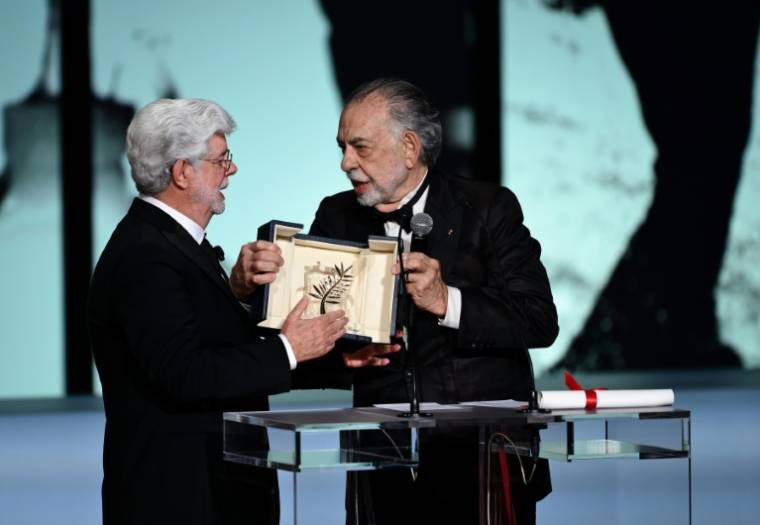 Le réalisateur américain George Lucas (G) reçoit la Palme d'or d'honneur des mains de Francis Ford Coppola lors de la cérémonie de clôture du 77e Festival de Cannes, le 25 mai 2024   ( AFP / Christophe SIMON )