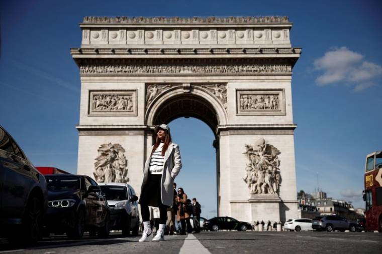 Une touriste posant devant l'Arc de Triomphe à Paris