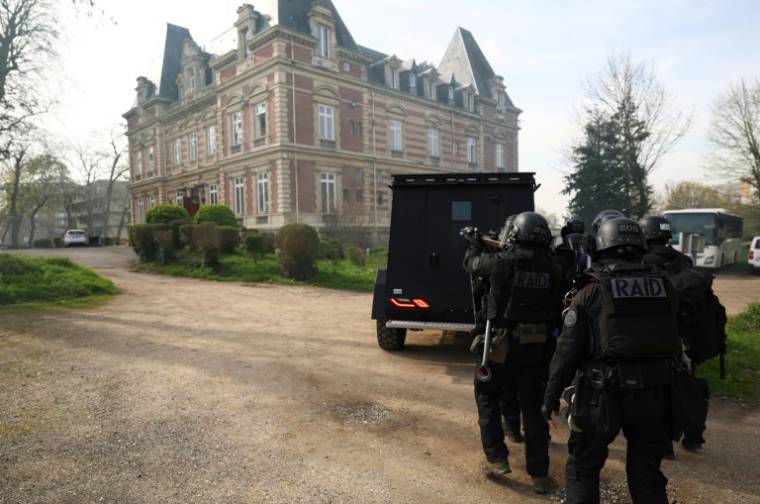 Des membres du Raid, à l'abri derrière le blindé "Black Wolf", participent à une simulation d'attaque terroriste, à l'école de police de Draveil, le 21 mars 2024 dans l'Essonne ( AFP / Emmanuel DUNAND )