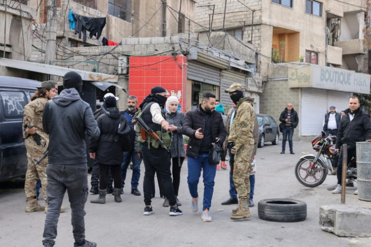 Des combattants affiliés à la nouvelle administration syrienne contrôlent les cartes d'identité à un point de contrôle après avoir fermé une route menant au quartier à majorité alaouite de Mazzeh 86 à Damas, le 26 décembre 2024 ( AFP / ANWAR AMRO )