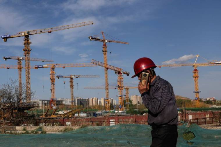 Un ouvrier passe devant un chantier de construction à Pékin