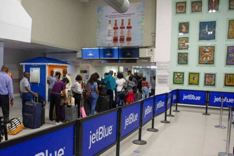 Des voyageurs font la queue pour embarquer à l'aéroport Toussaint-Louverture de Port-au-Prince, le 20 mai 2024 en Haïti ( AFP / Clarens SIFFROY )