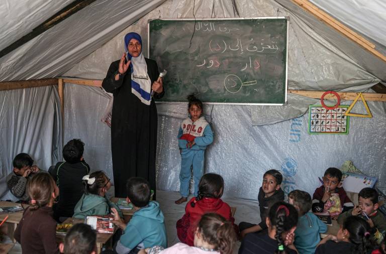 Une enseignante fait un cours à ses élèves le 27 mars 2024 dans une tente d'un camp de déplacés palestiniens à Rafah, dans le sud de la bande de Gaza, où une guerre oppose Israël au mouvement islamiste Hamas ( AFP / SAID KHATIB )