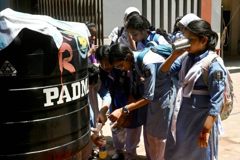 Des élèves remplissent leurs bouteilles lors d'une chaude journée dans une école de Dhaka, le 28 avril 2024 ( AFP / Munir UZ ZAMAN )