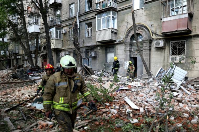 Des sauveteurs devant un immeuble touché par une frappe russe à Dnipro, le 19 avril 2024 en Ukraine ( AFP / Anatolii Stepanov )