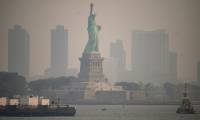 La Statue de la Liberté vue depuis un ferry le 6 juin 2023 alors que New York est enveloppé d'un brouillard de fumées dû à des feux de forêt au Québec ( AFP / Ed JONES )