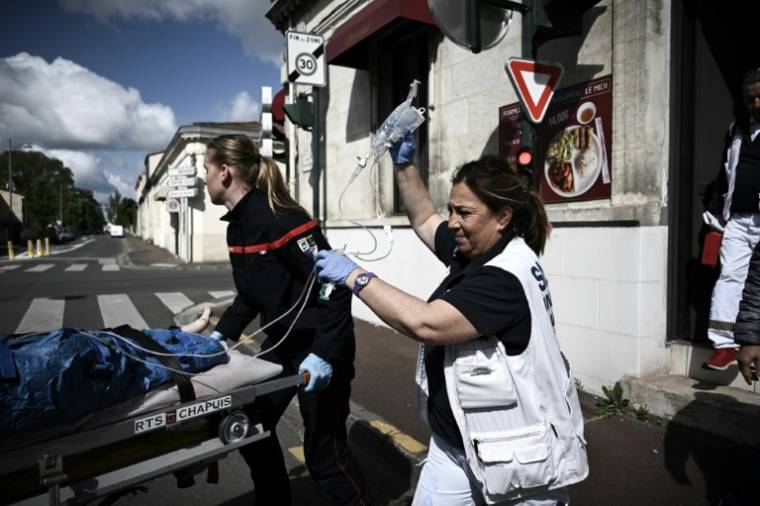 Pascale Martinet (d), infirmière anesthésiste et membre de l'une des premières unités hospitalières mobiles paramédicales (UMH-P) du CHU de Bordeaux, s'occupe d'une femme lors de son transport vers une clinique suite à un appel d'urgence, le 17 avril 2024 à Bordeaux ( AFP / Philippe LOPEZ )