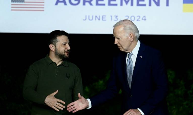 Le président ukrainien Volodymyr Zelensky (g) et son homologue américain Joe Biden se serrent la main après avoir signé un accord de sécurité bilatéral lors d'une conférence de presse en marge du G7, le 13 juin 2024 à Savelletri, en Italie ( AFP / Filippo MONTEFORTE )
