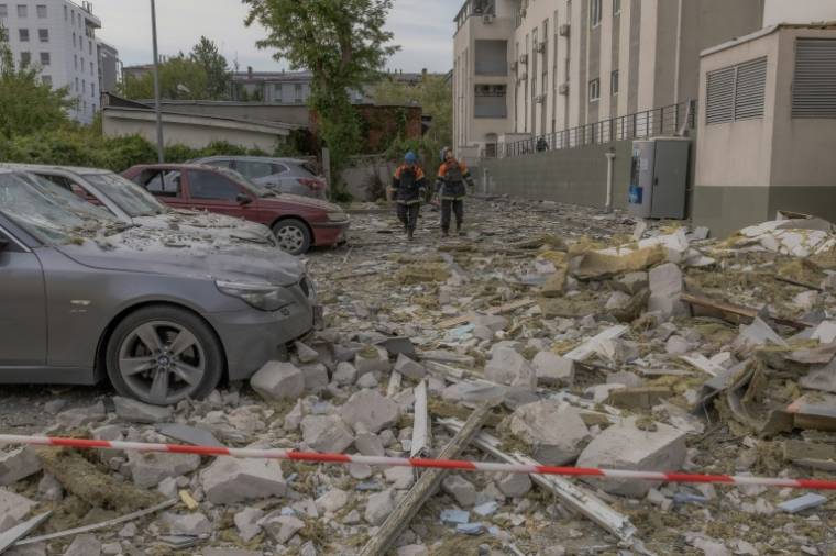 Des secouristes dans des débris devant un immeuble touché par une frappe, le 14 mai 2024 à Kharkiv, en Ukraine ( AFP / Roman PILIPEY )