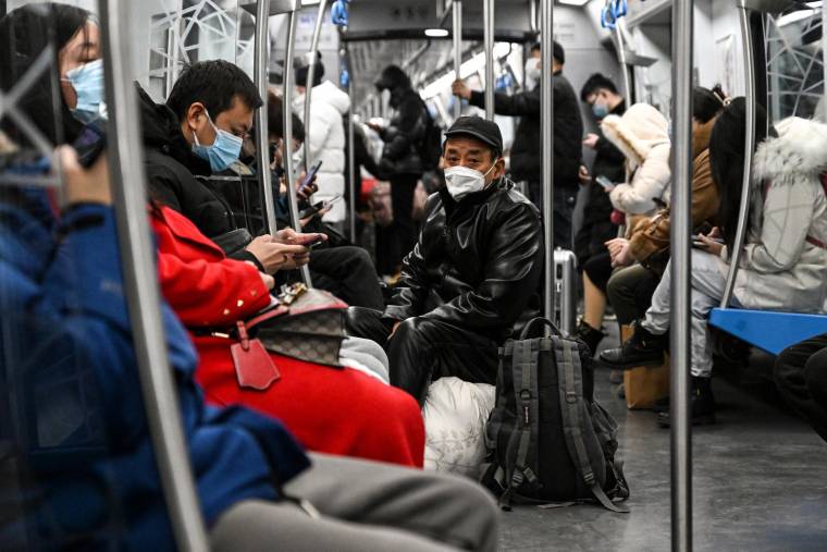 Passagers portant leur masque dans un train en pleine épidémie de Covide-19 à Pékin, le 19 décembre 2022 ( AFP / Noel CELIS )